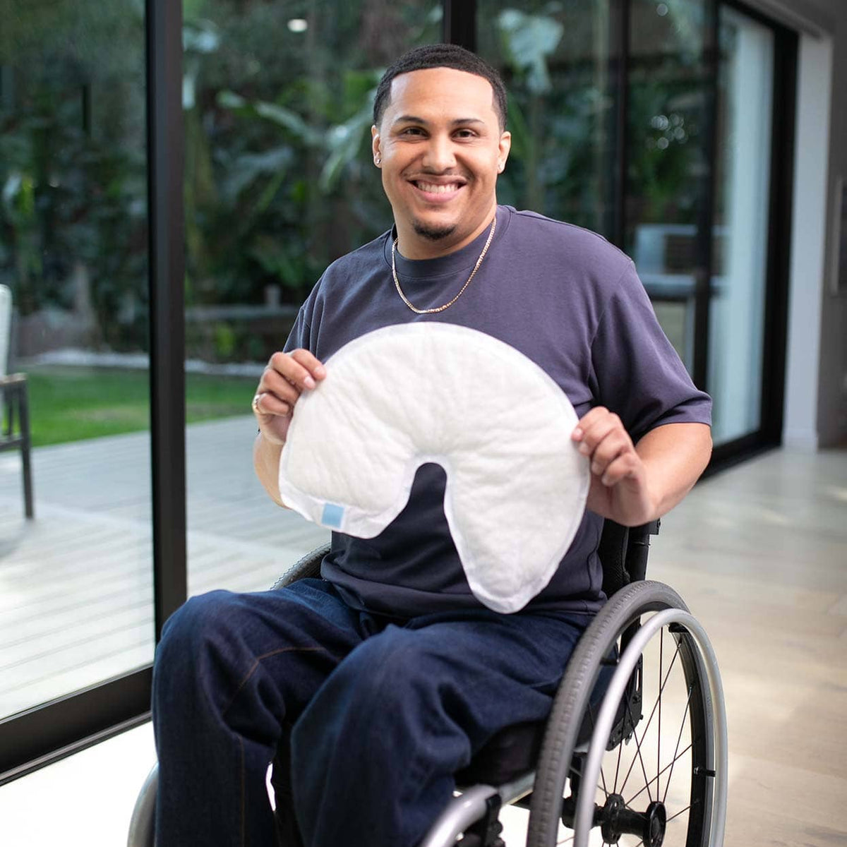 Man in a wheelchair holding a QC Wrap in an indoor setting with large windows.