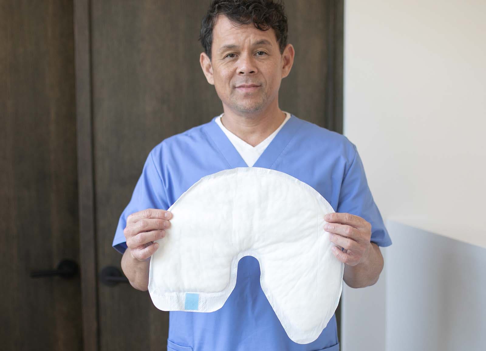 A nurse in blue scrubs holds up a QuickChange Maximum Absorbency Wrap.
