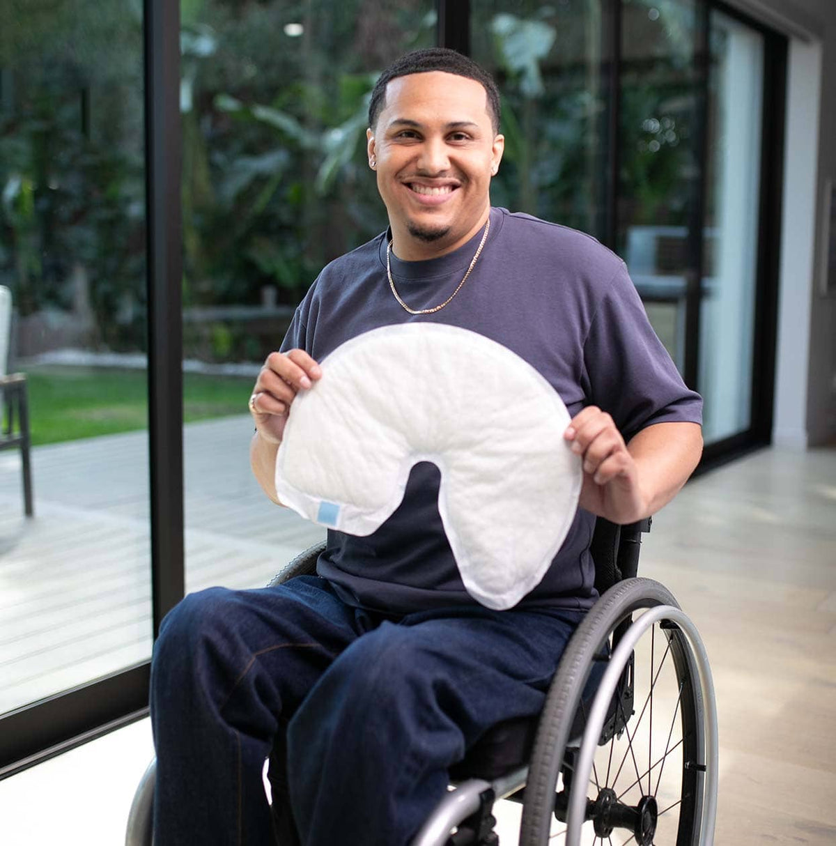 Man in a wheelchair holding a QC Wrap in an indoor setting with large windows.